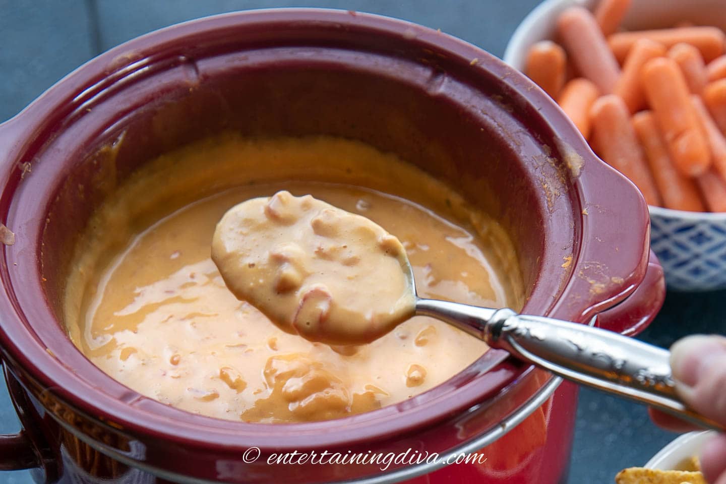 Velveeta Rotel cheese dip on a spoon above a Crockpot