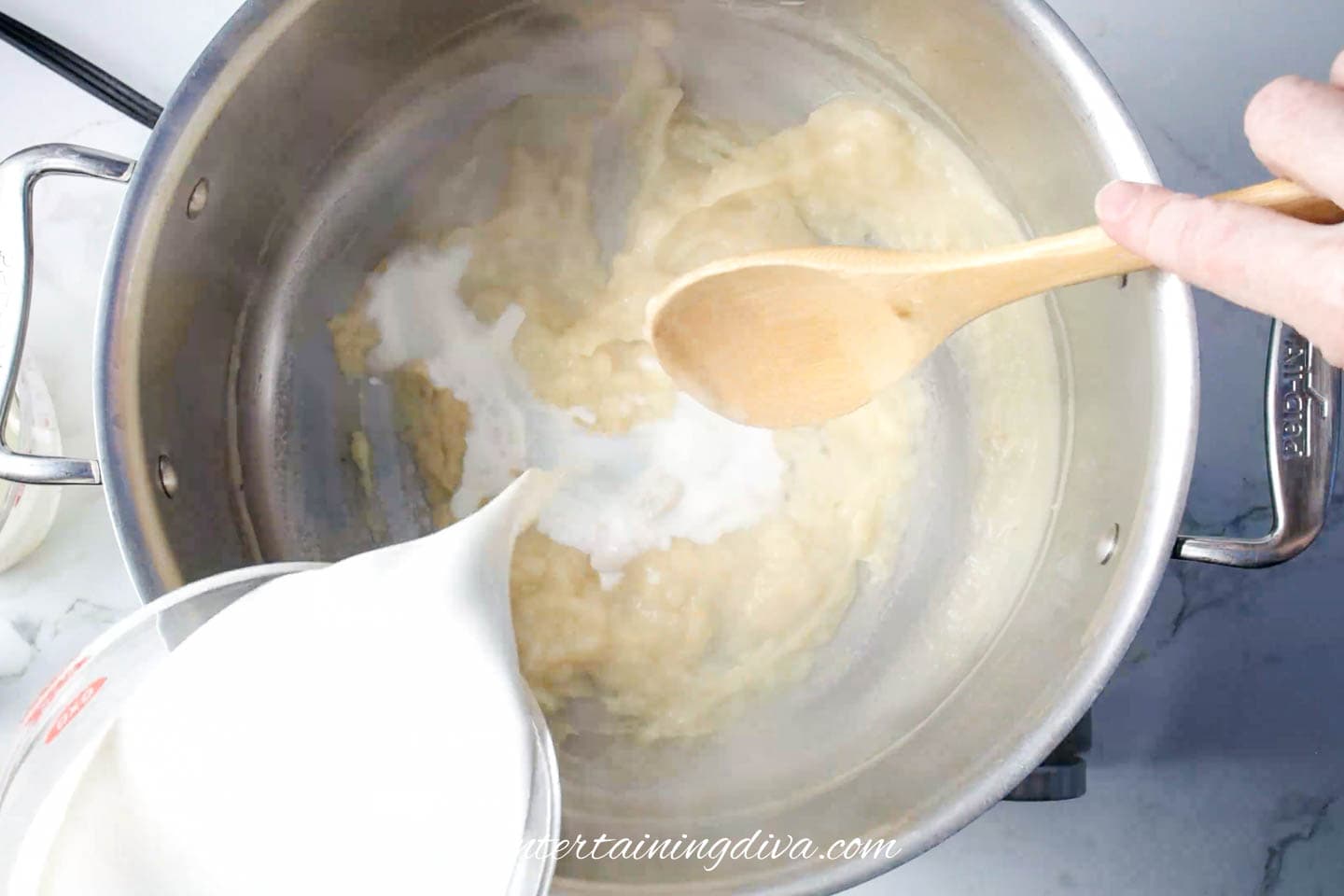 milk being added to onion mixture in pot