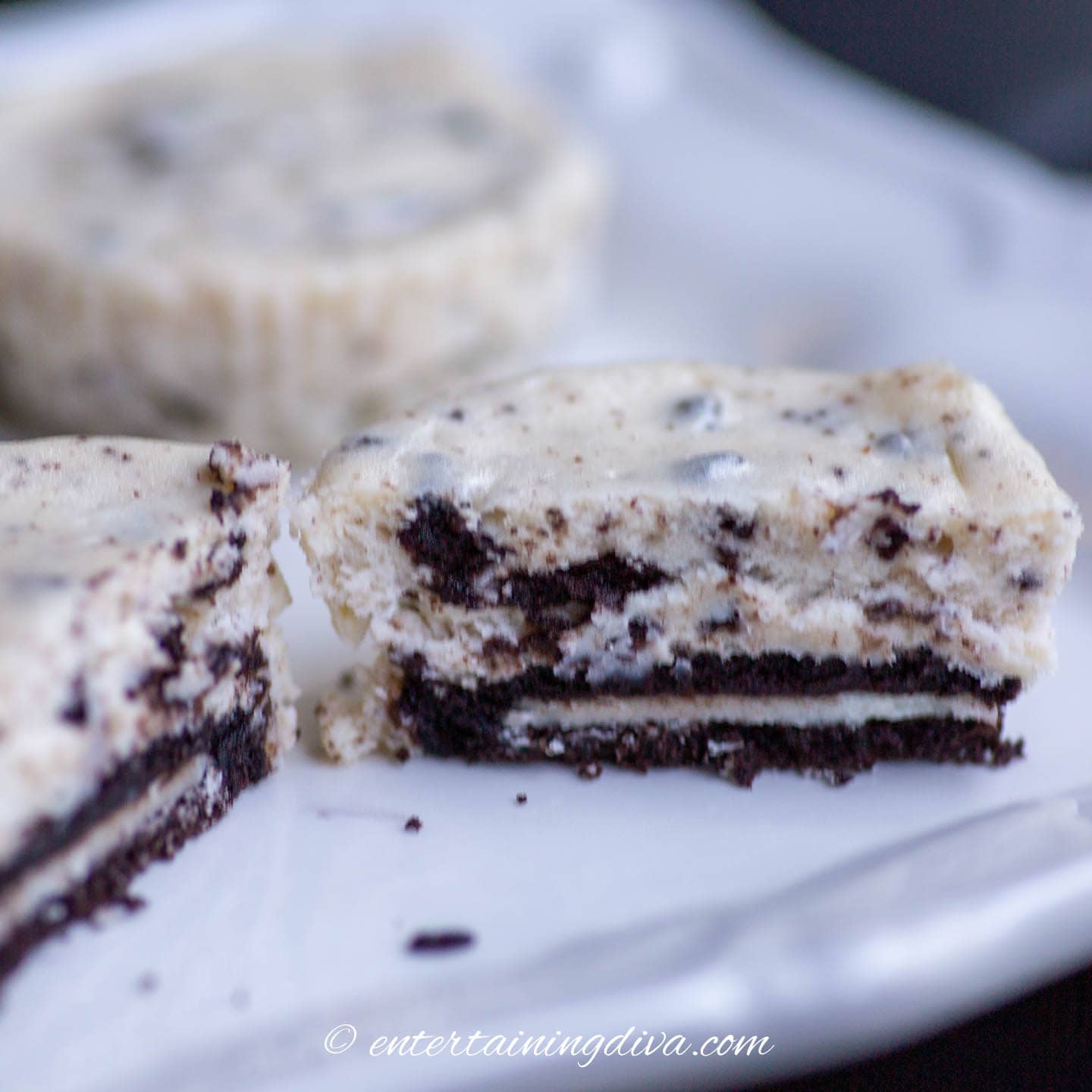 black and white Oreo cheesecake cupcakes cut in half on a plate