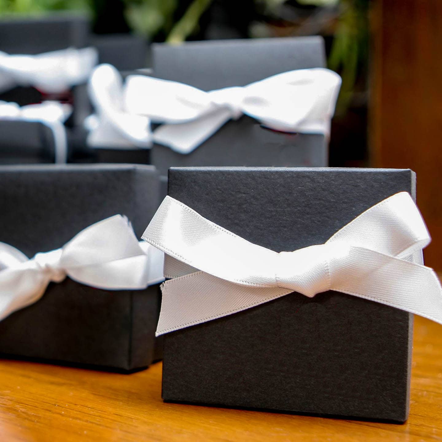 black party favor boxes with white ribbons on them