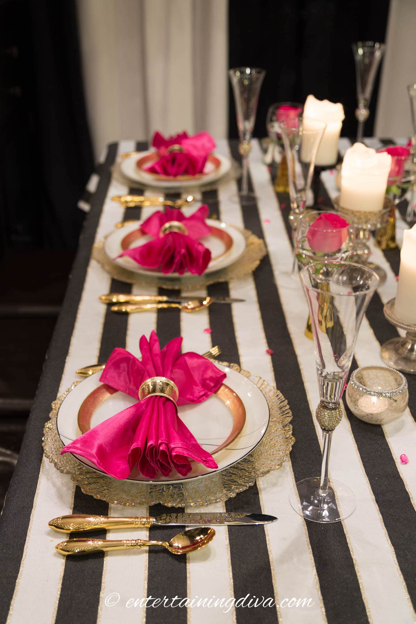 black, white and pink table setting with a black and white striped tablecloth.