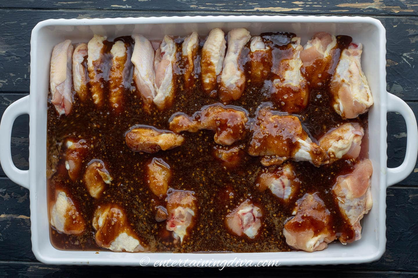 Easy baked sticky Chinese chicken wings in the pan with sauce poured over the top before baking