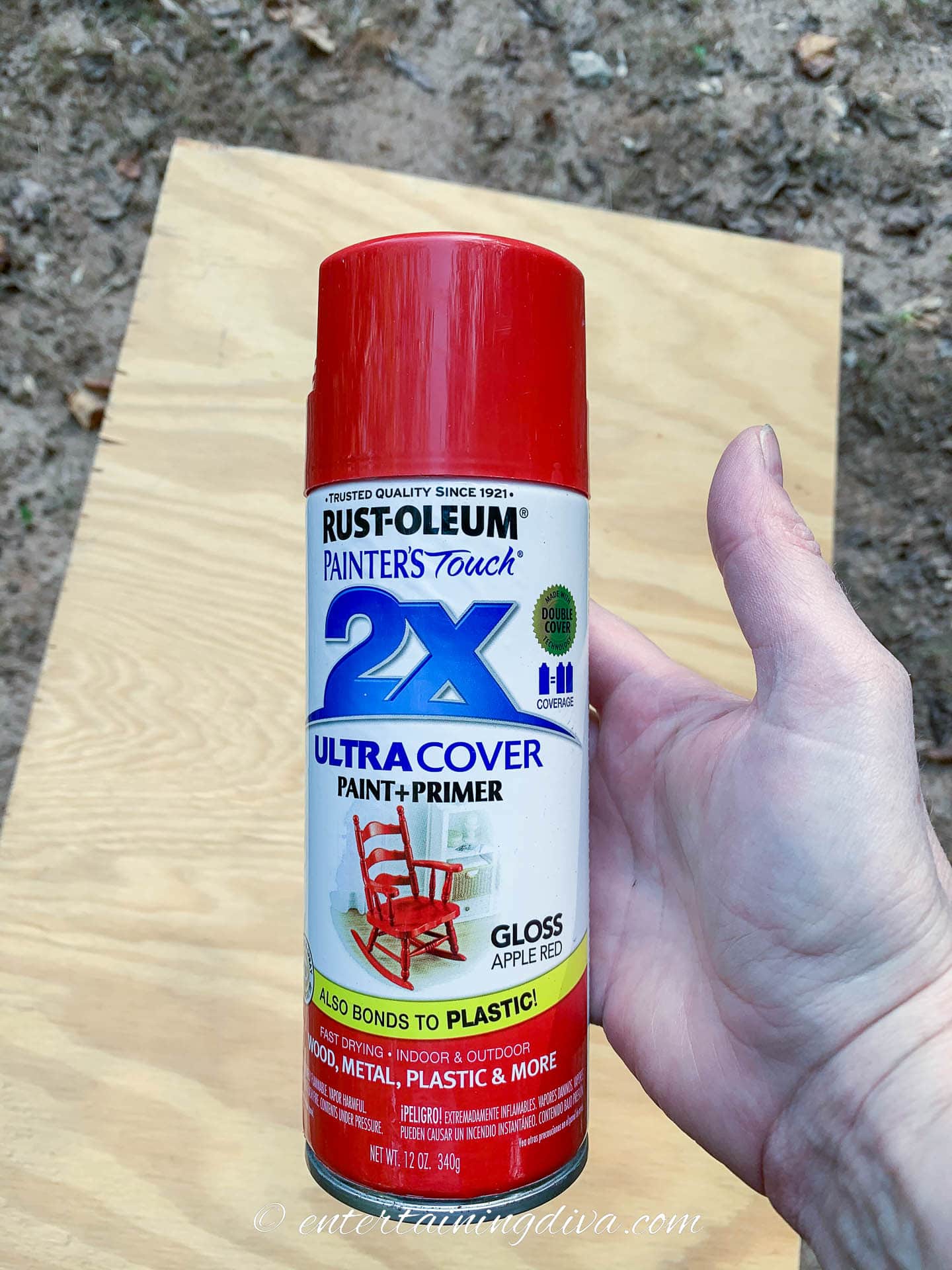 Can of red spray paint in front of a piece of plywood