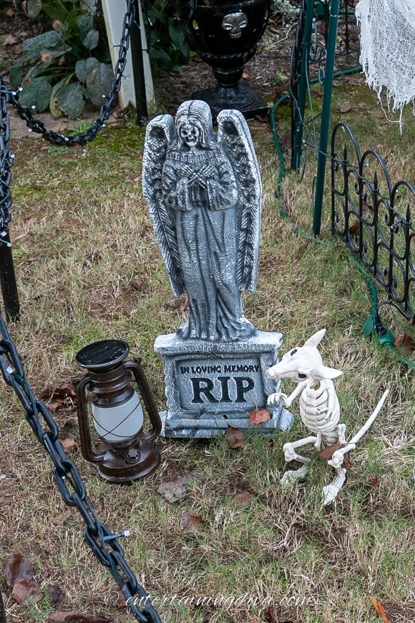 Skeleton rat and a lantern in front of a Halloween tombstone