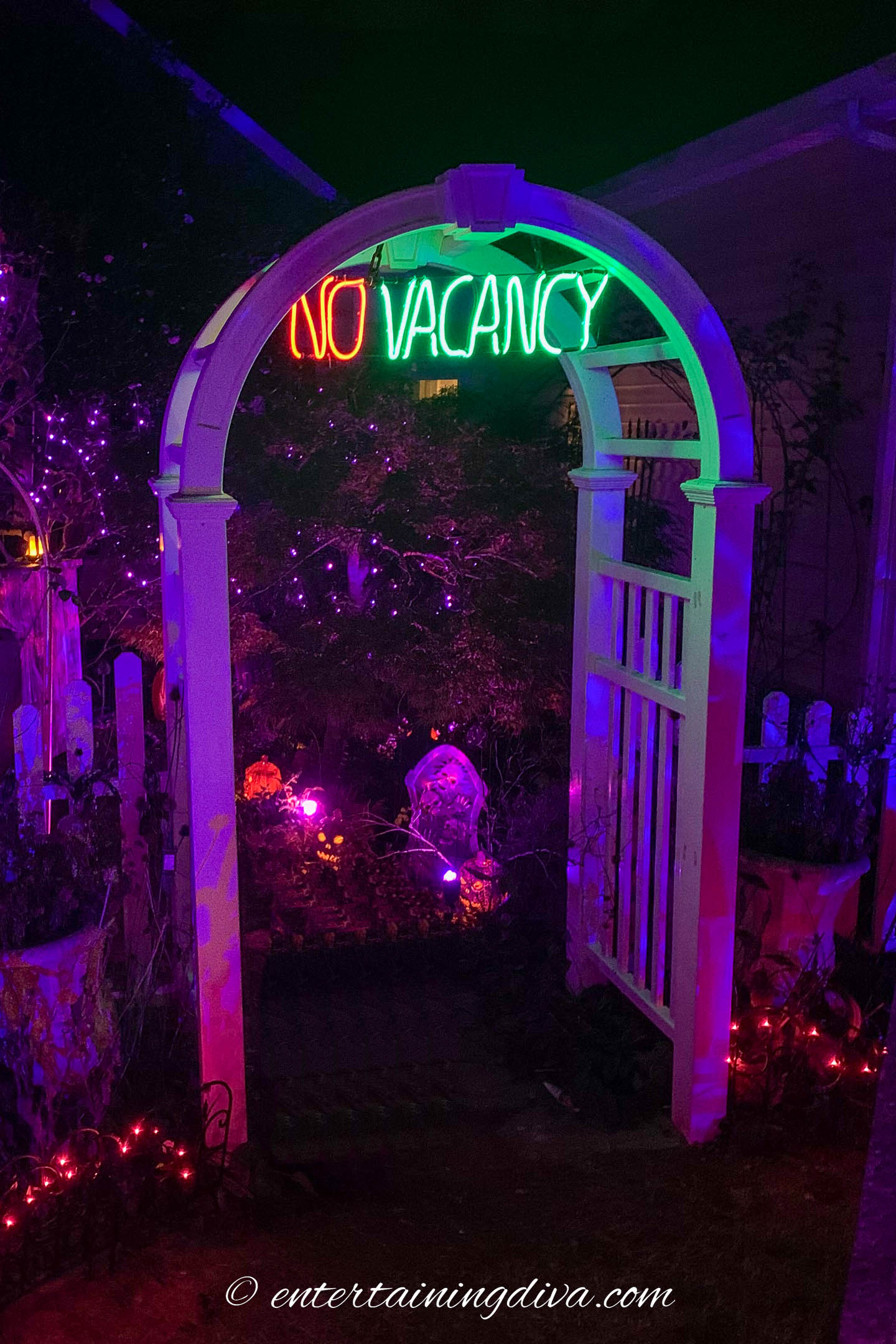 No Vacancy neon sign hung in an arbor decorated for Halloween