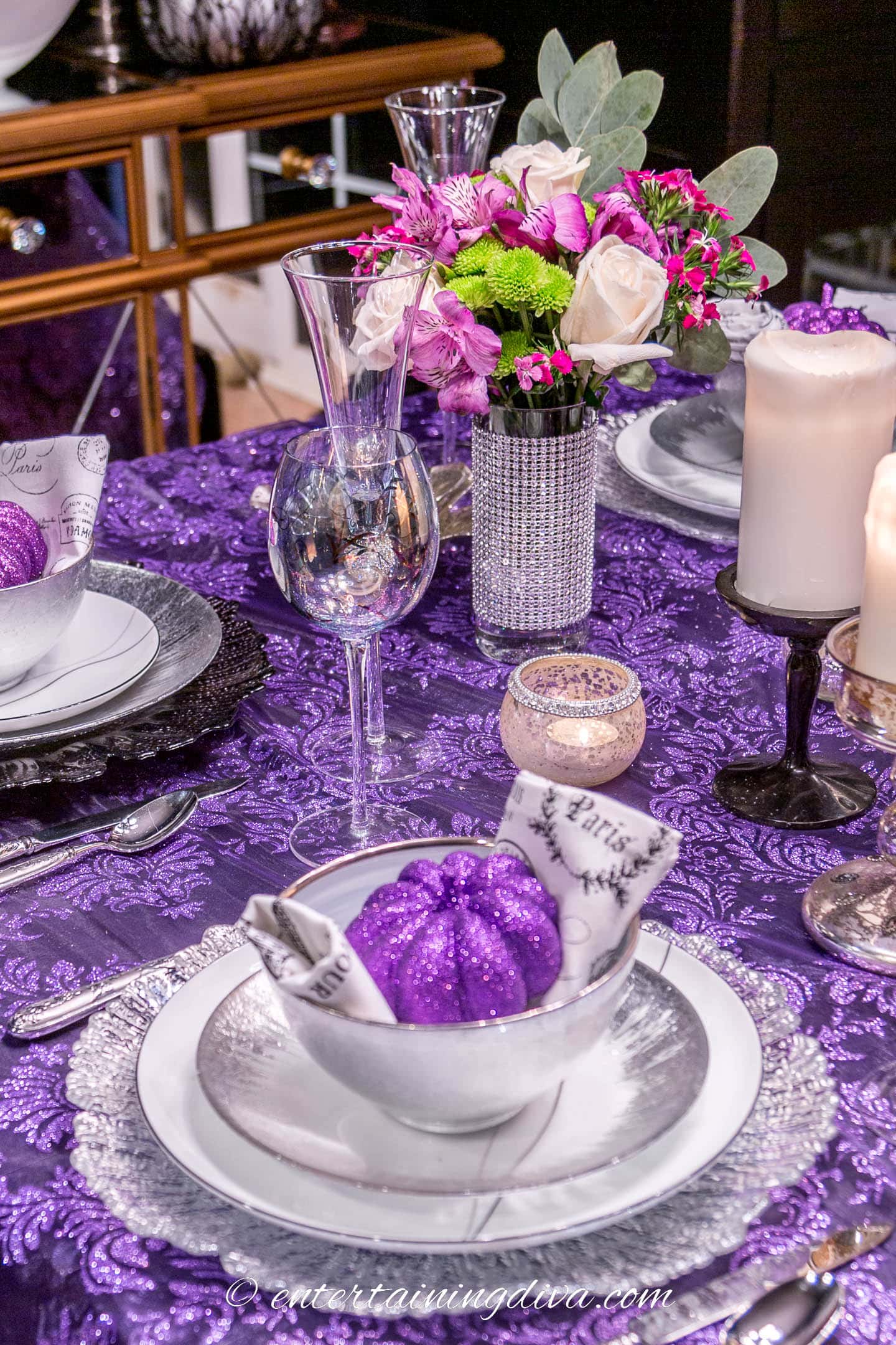 Purple, black and silver Halloween table decor with flower centerpiece and white candles