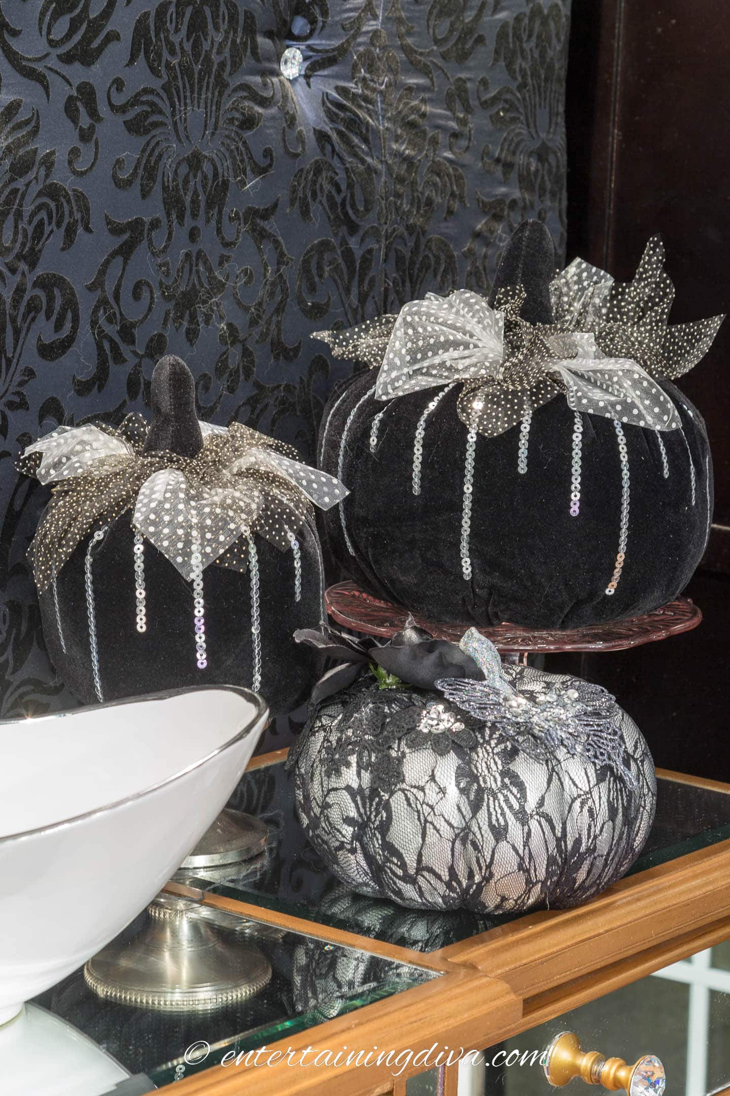 Three black and silver velvet pumpkins on a buffet table