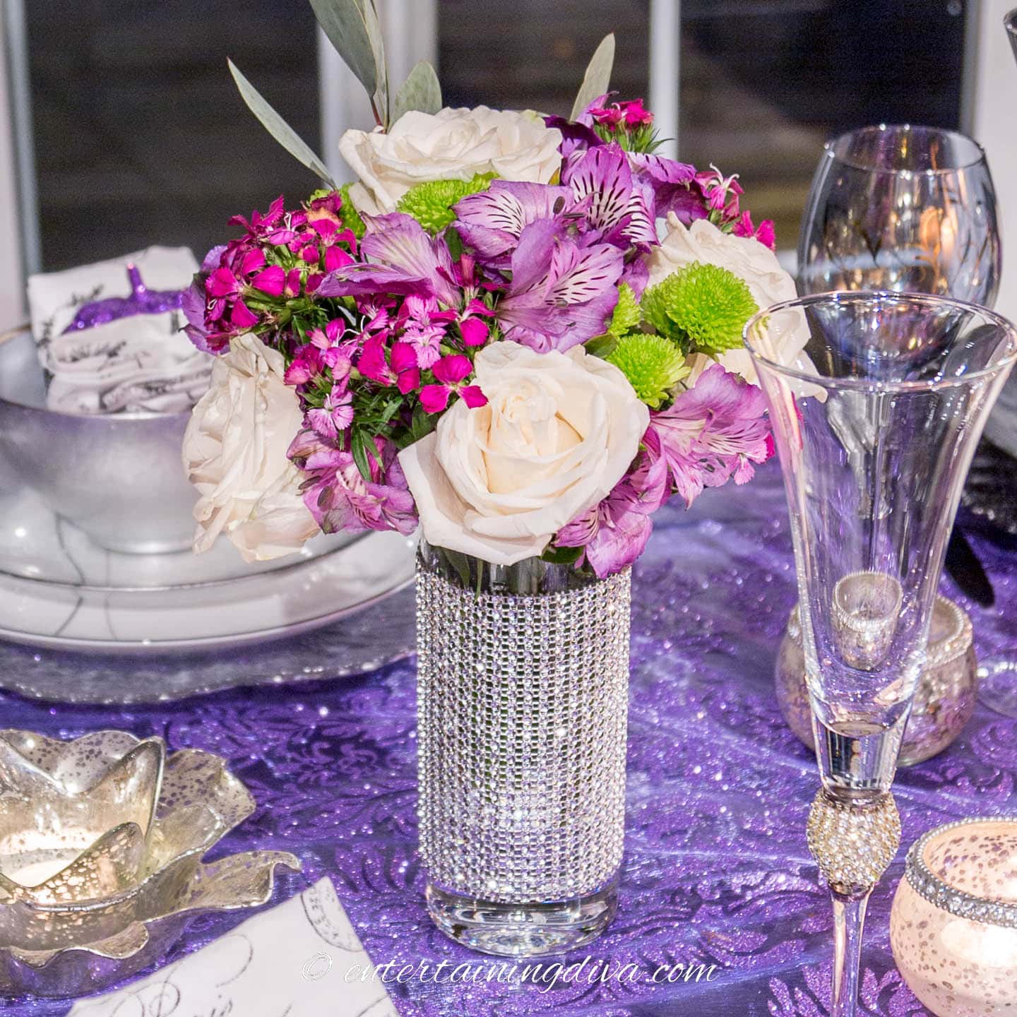 A small bunch of purple white and green flowers on a purple, black and silver Halloween tablescape