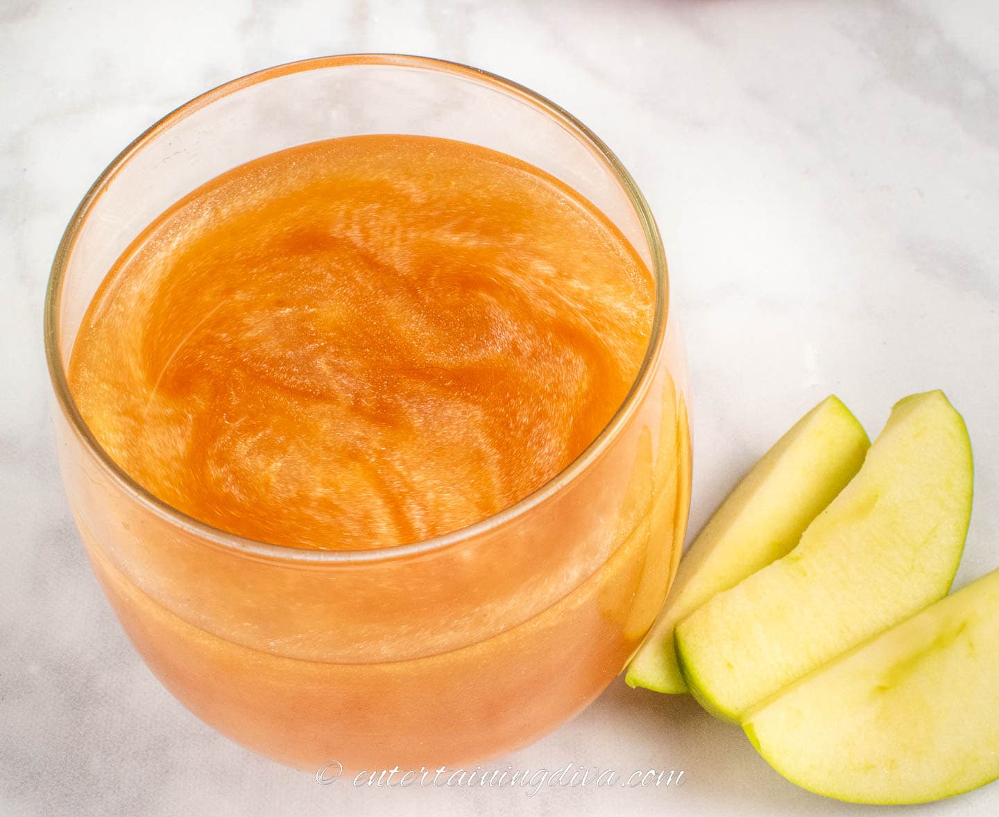 fireball and hard apple cider cocktail in a glass beside some apple slices