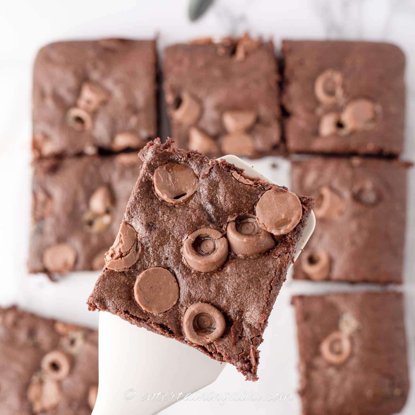 Close up of a rolo brownie being held up over the rest of the brownie squares