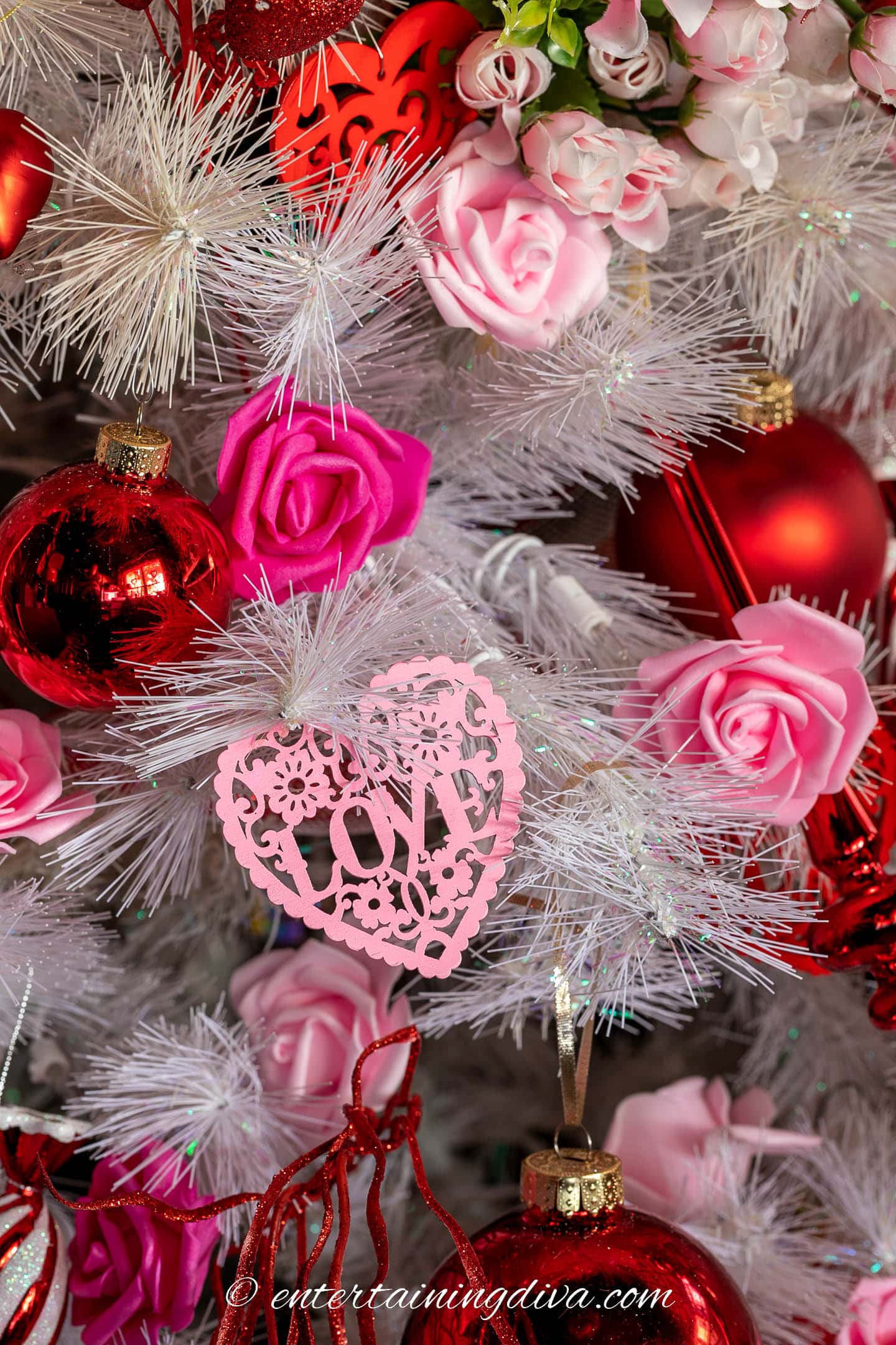 Wood heart ornament with faux roses on a white Christmas tree for Valentine's Day