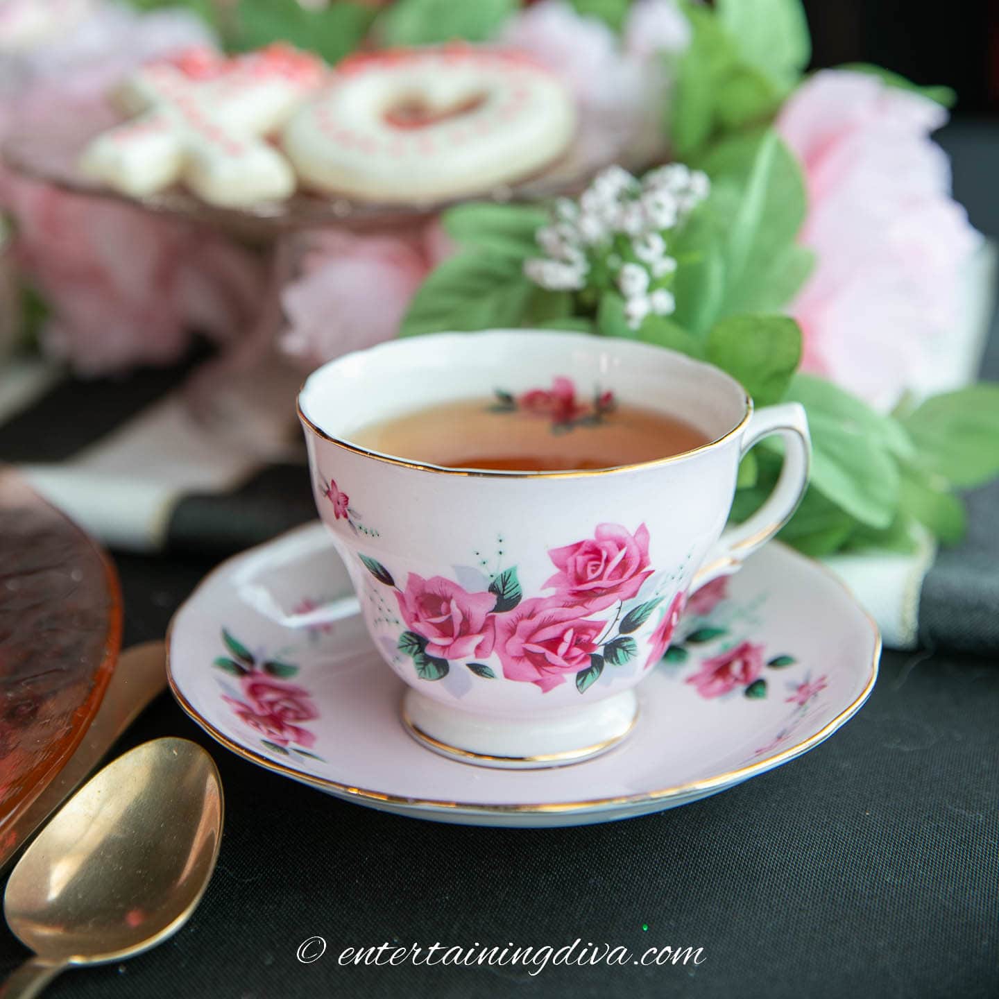 A teacup and saucer with flowers in the background