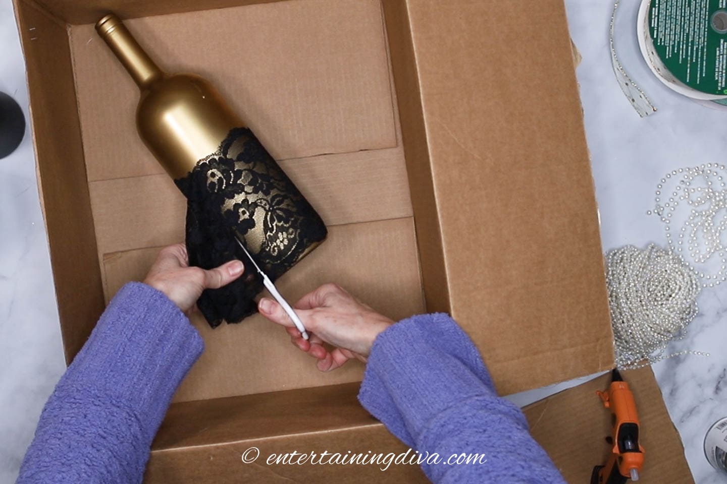 black lace being cut off from the gold wine bottle
