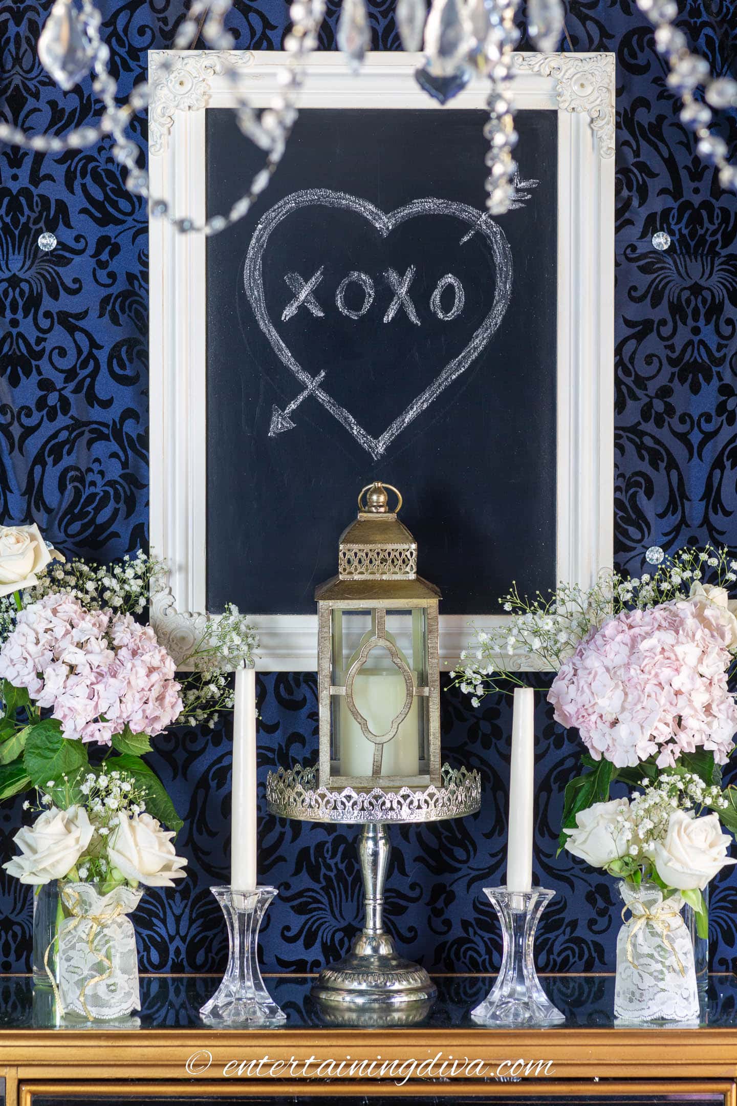 Framed chalkboard with a heart drawn in the middle above a gold candle lantern
