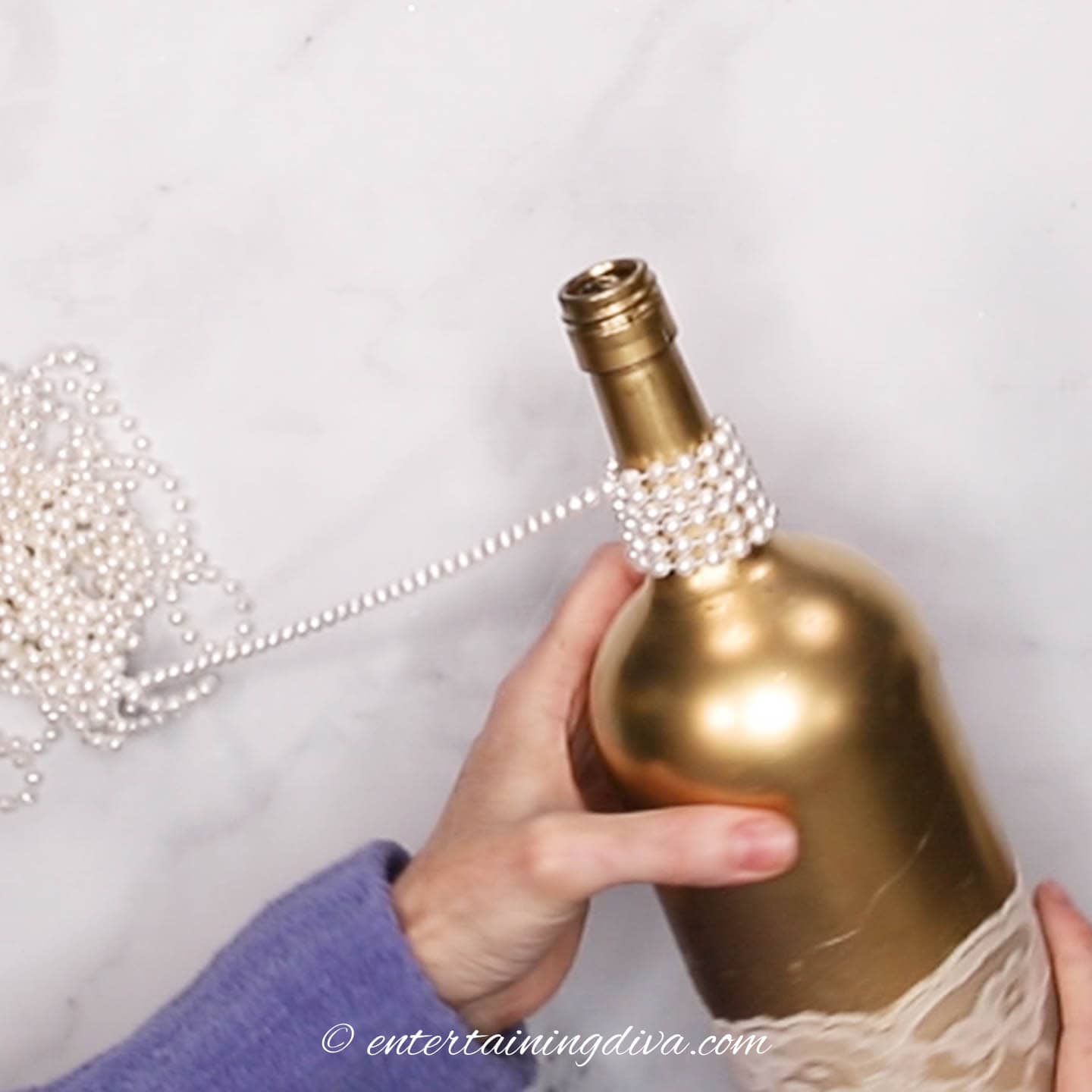 String of pearls being wound around the neck of a wine bottle