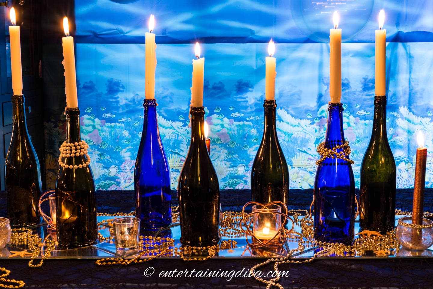 A group of black and blue wine bottles decorated with beads and candles