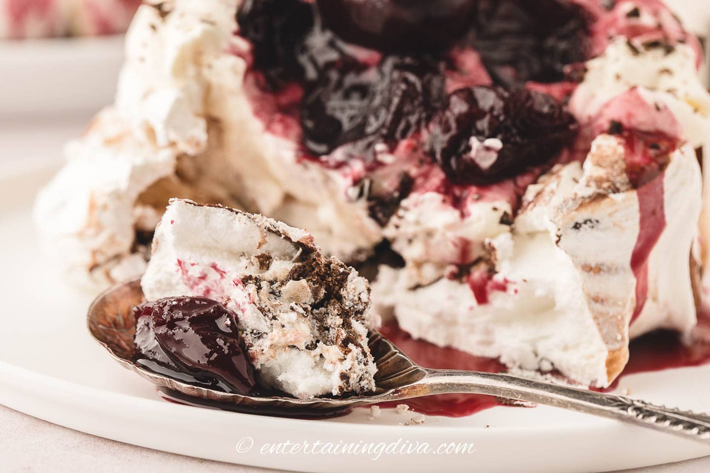A spoonful of black forest pavlova in front of the rest of the dessert