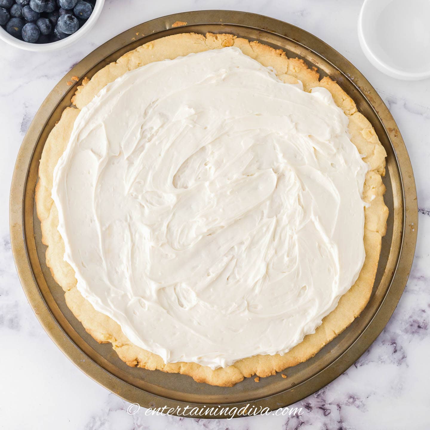 Cream cheese frosting spread on top of a sugar cookie crust