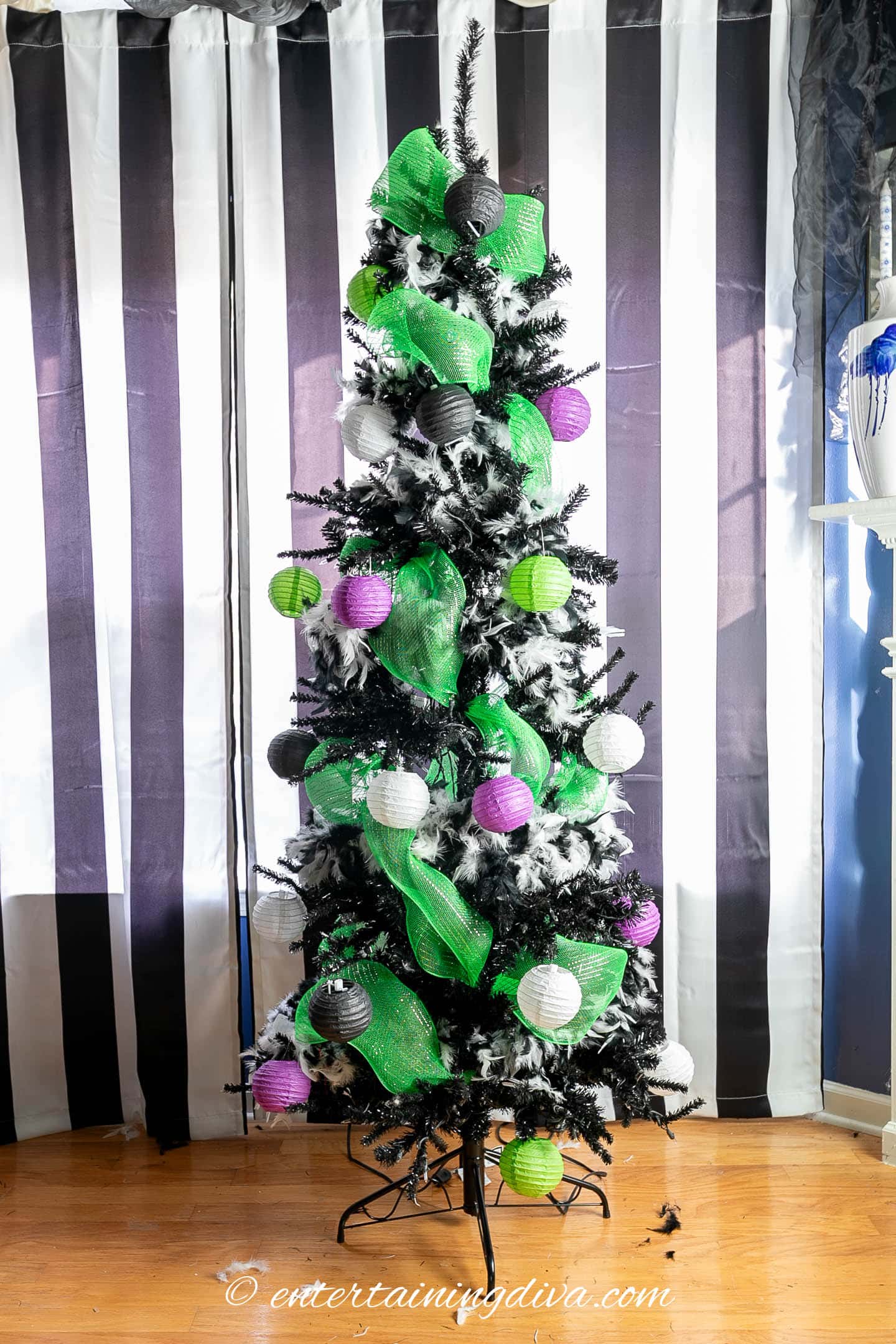 Small black, white, purple and green paper lanterns hung on a black Halloween tree 