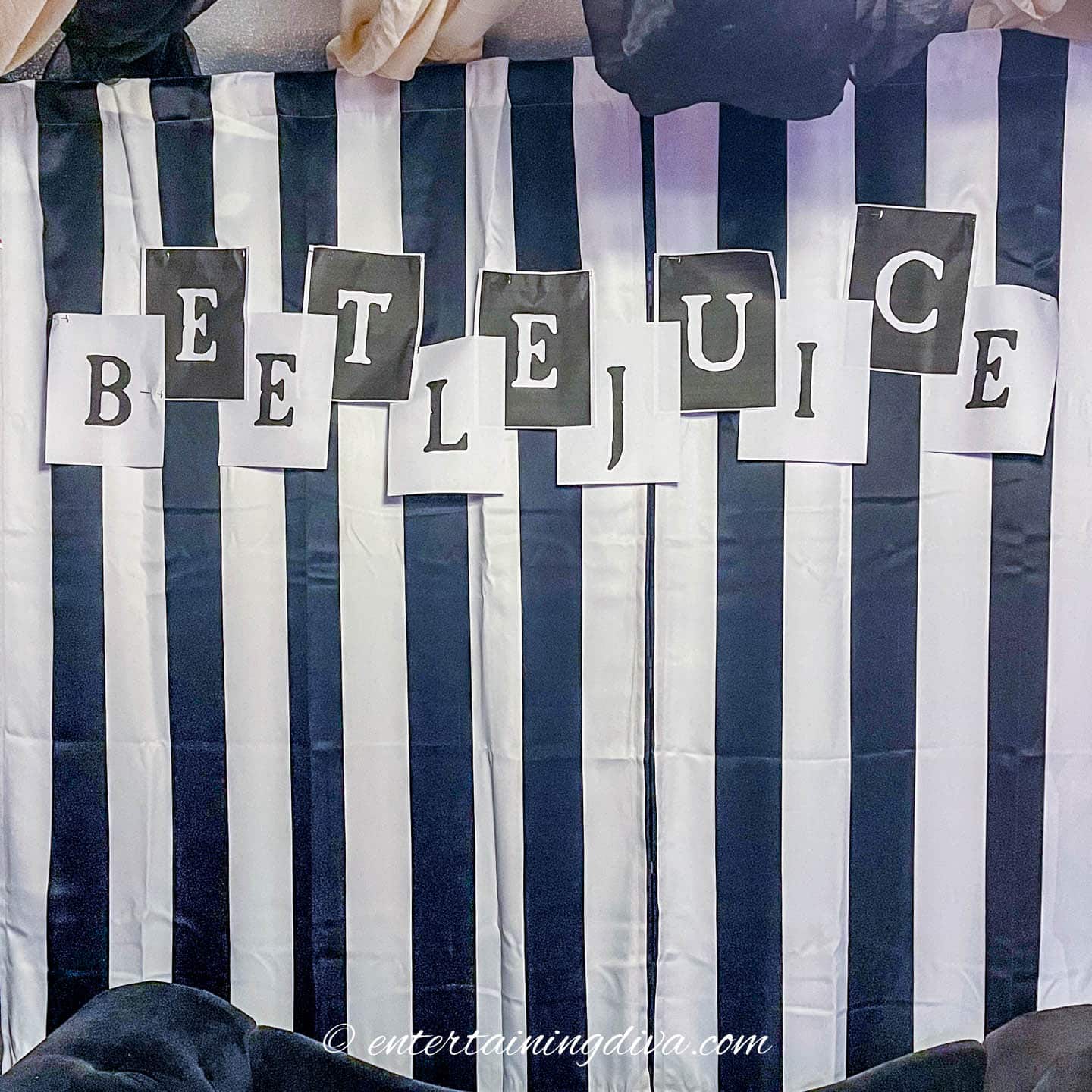 DIY Beetlejuice banner hung on black and white striped curtains