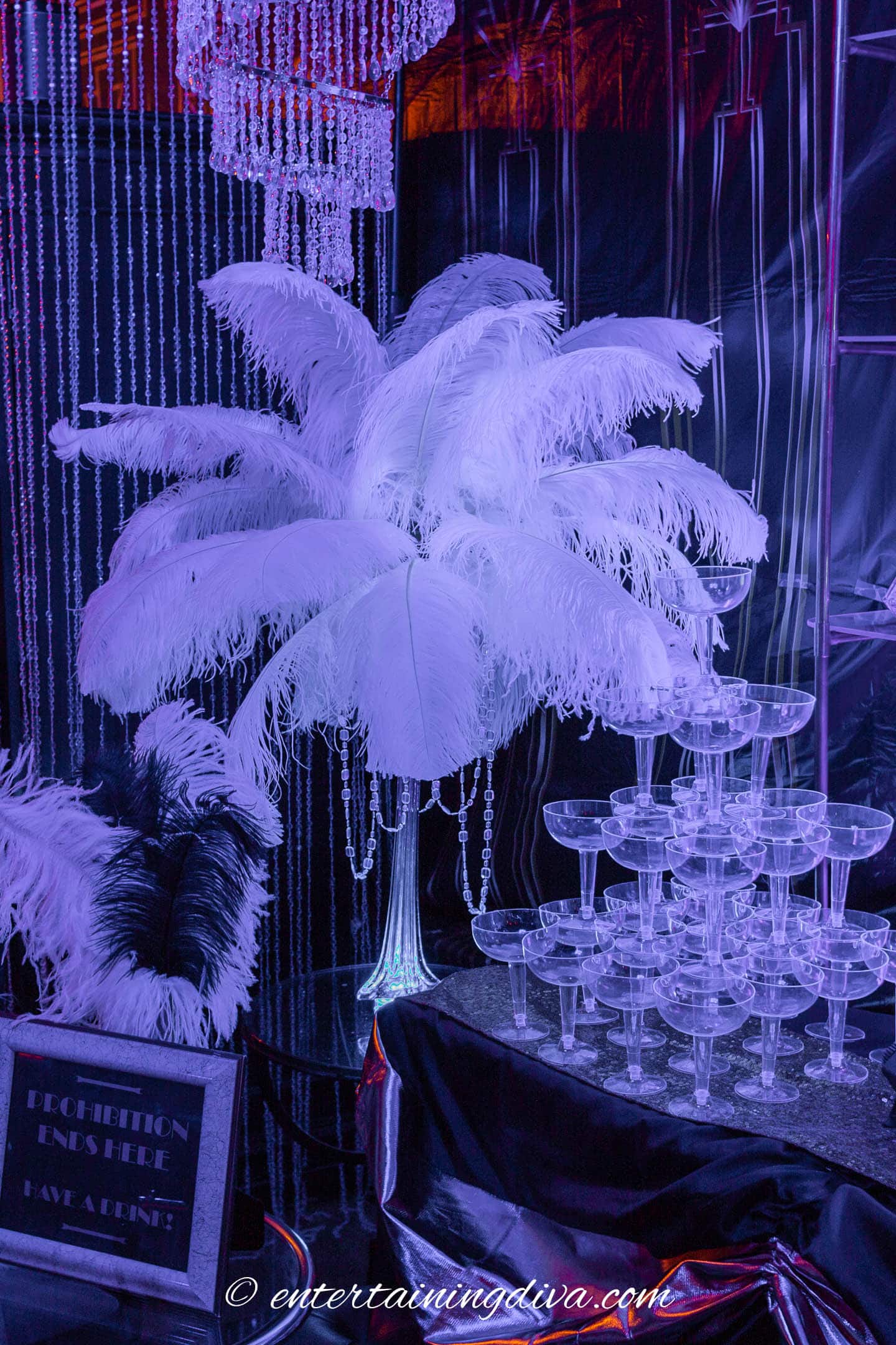 DIY Gatsby ostrich feather centerpiece beside a DIY champagne glass tower