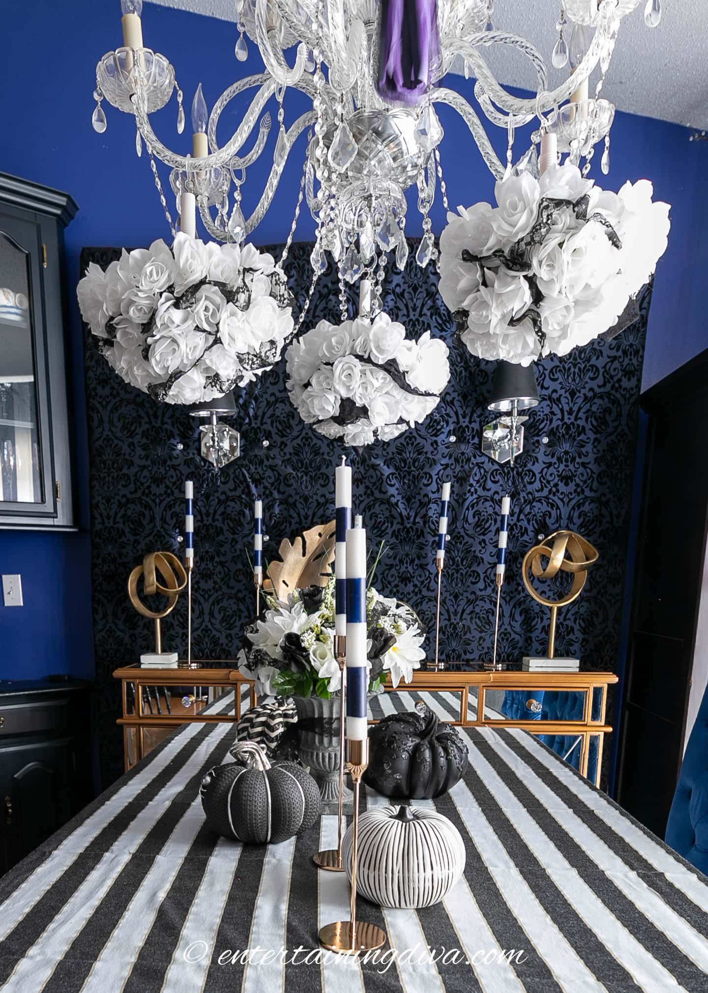 Beetlejuice dinner party table with a black and white striped tablecloth and black and white pumpkins and candles as the centerpiece