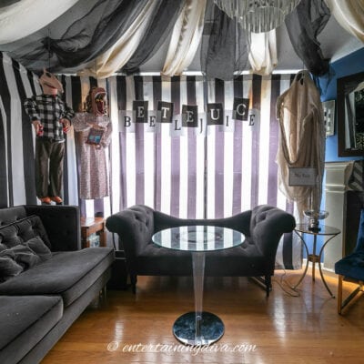 A beetlejuice themed living room with black and white striped curtains.