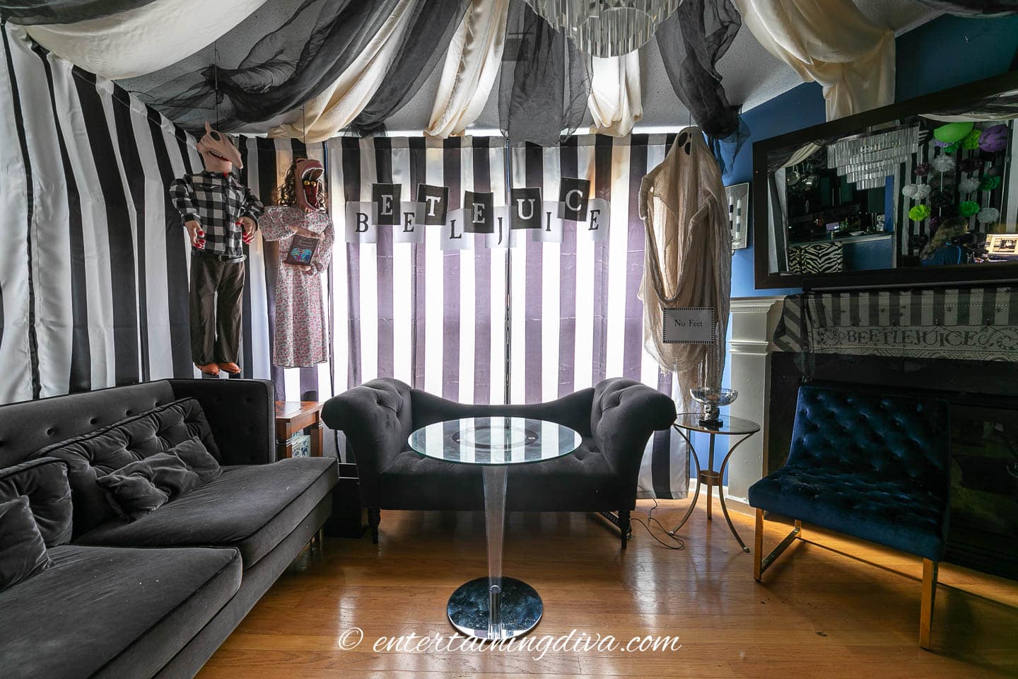 A living room at a Beetlejuice party decorated with black and white striped curtains.