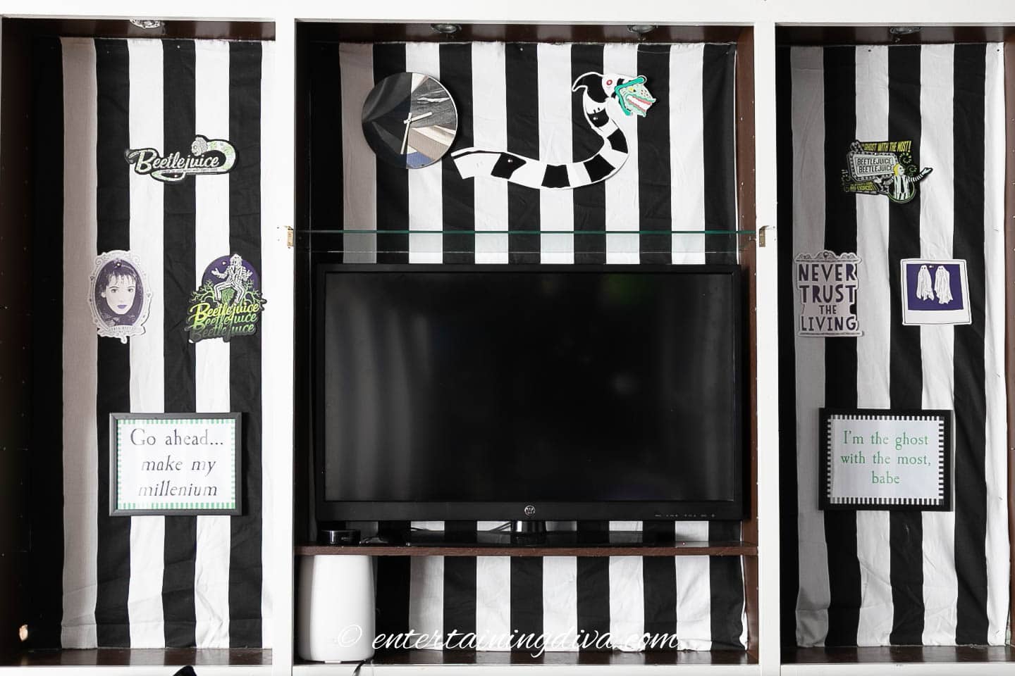 A black and white striped bookshelf with a tv and Beetlejuice decorations.