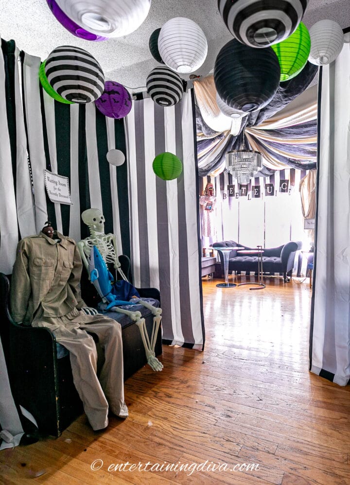 The Beetlejuice party waiting room decorated with black and white paper lanterns and skeletons dressed like shrunken head man and dead surfer