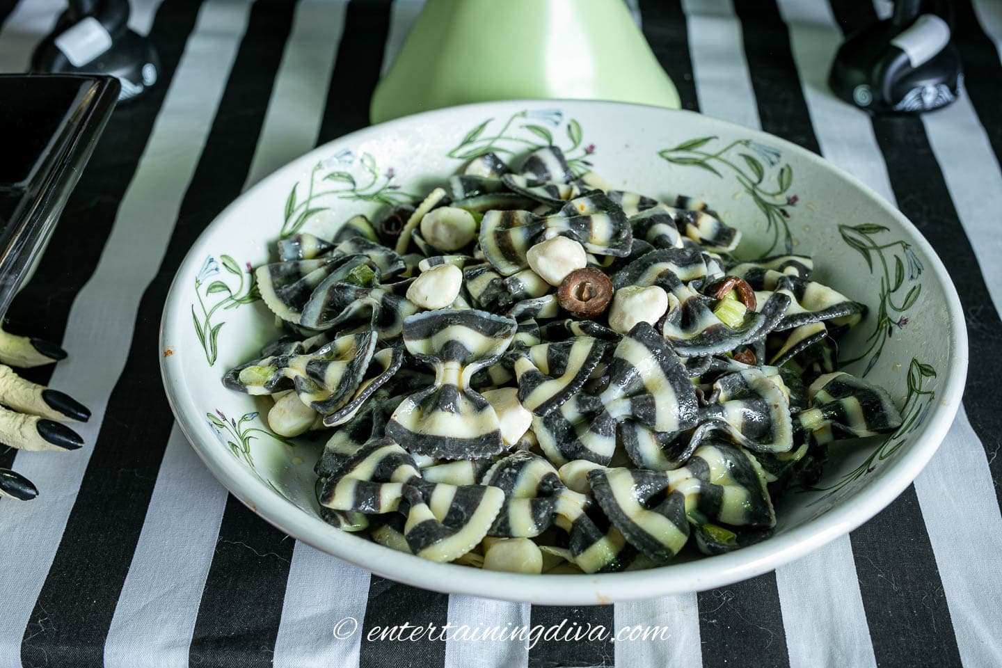 A black and white striped tablecloth with black and white pasta salad in a bowl.