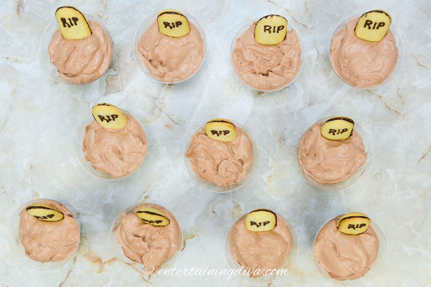 A group of Halloween pudding cups with tombstone cookies on them