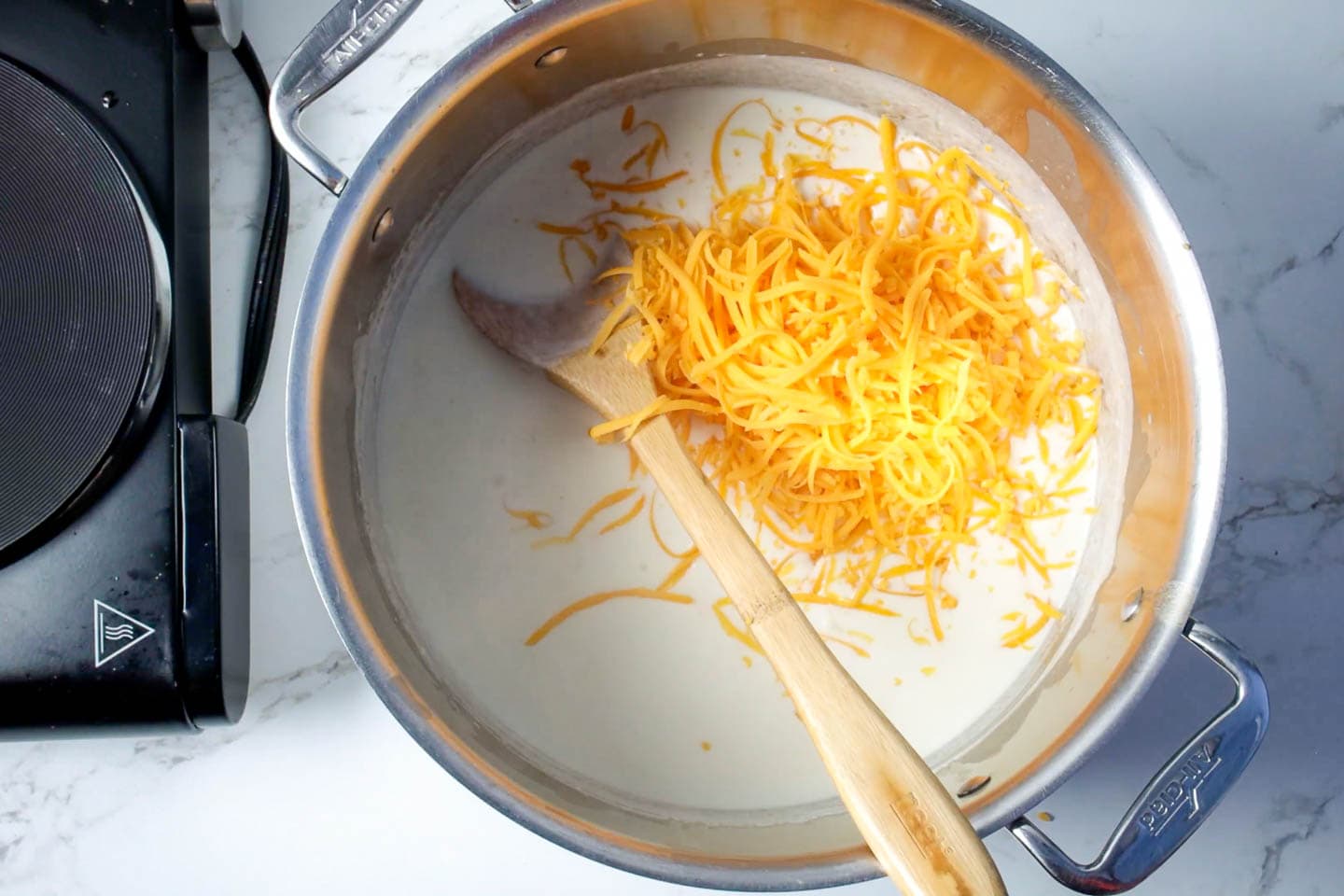 Grated cheese in the heated milk mixture with a wooden spoon.