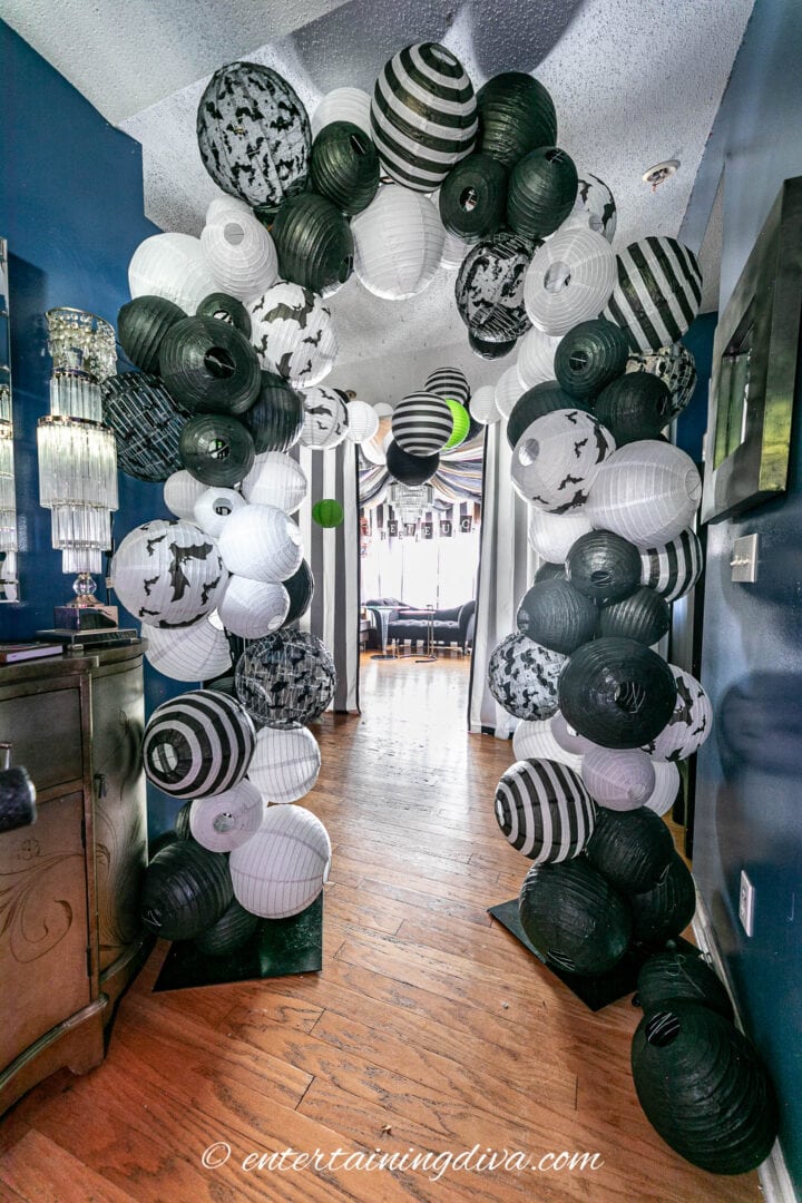 A DIY black and white paper lantern arch at the entrance to a Beetlejuice party.