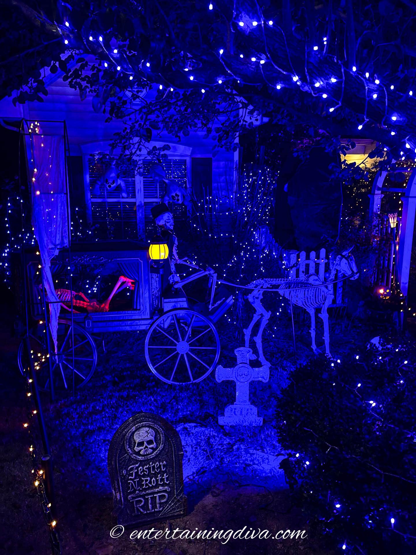 A skeleton in a carriage with blue lights for Halloween outdoor lighting.