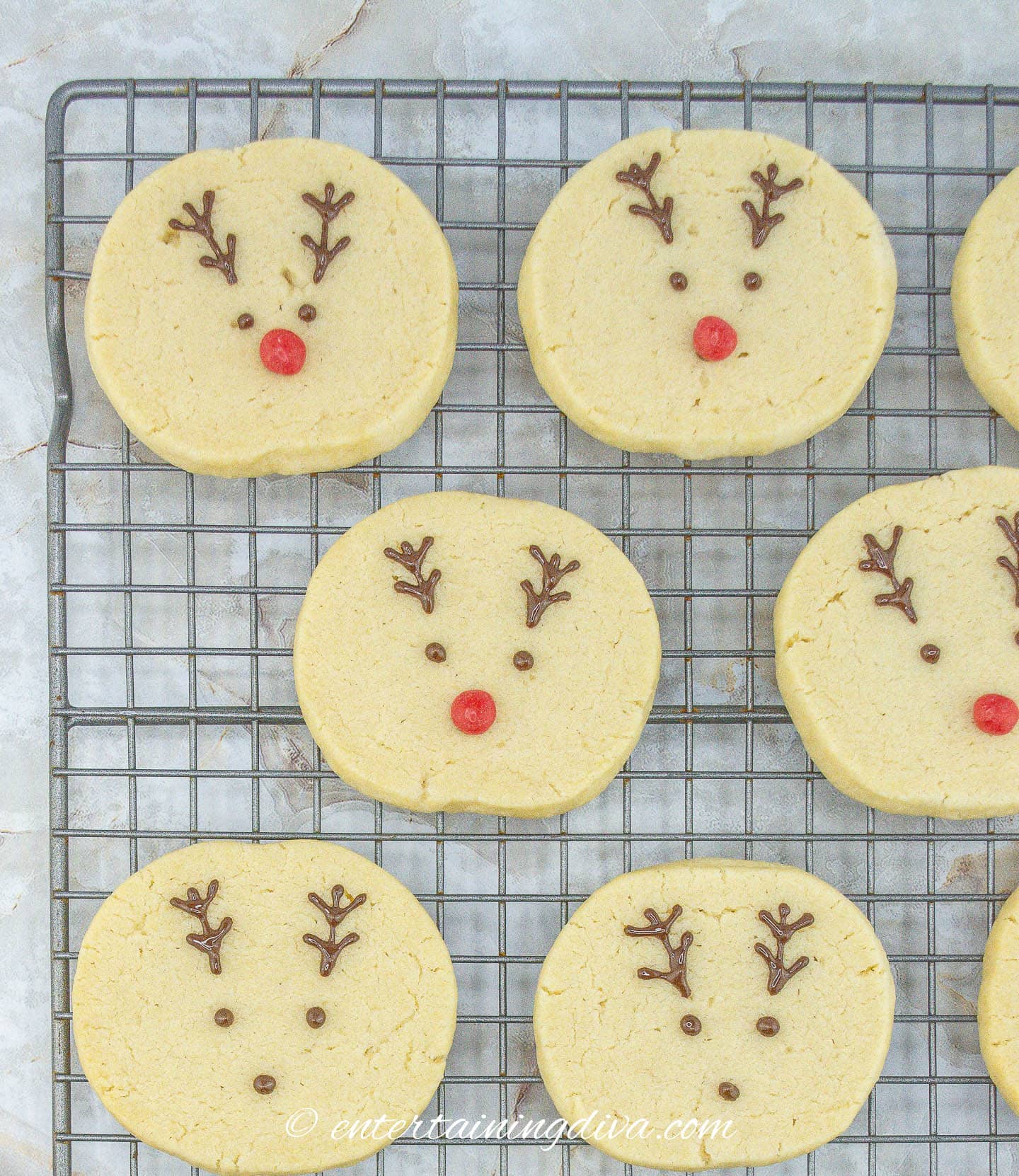 Decorated reindeer sugar cookies on a cooling rack.