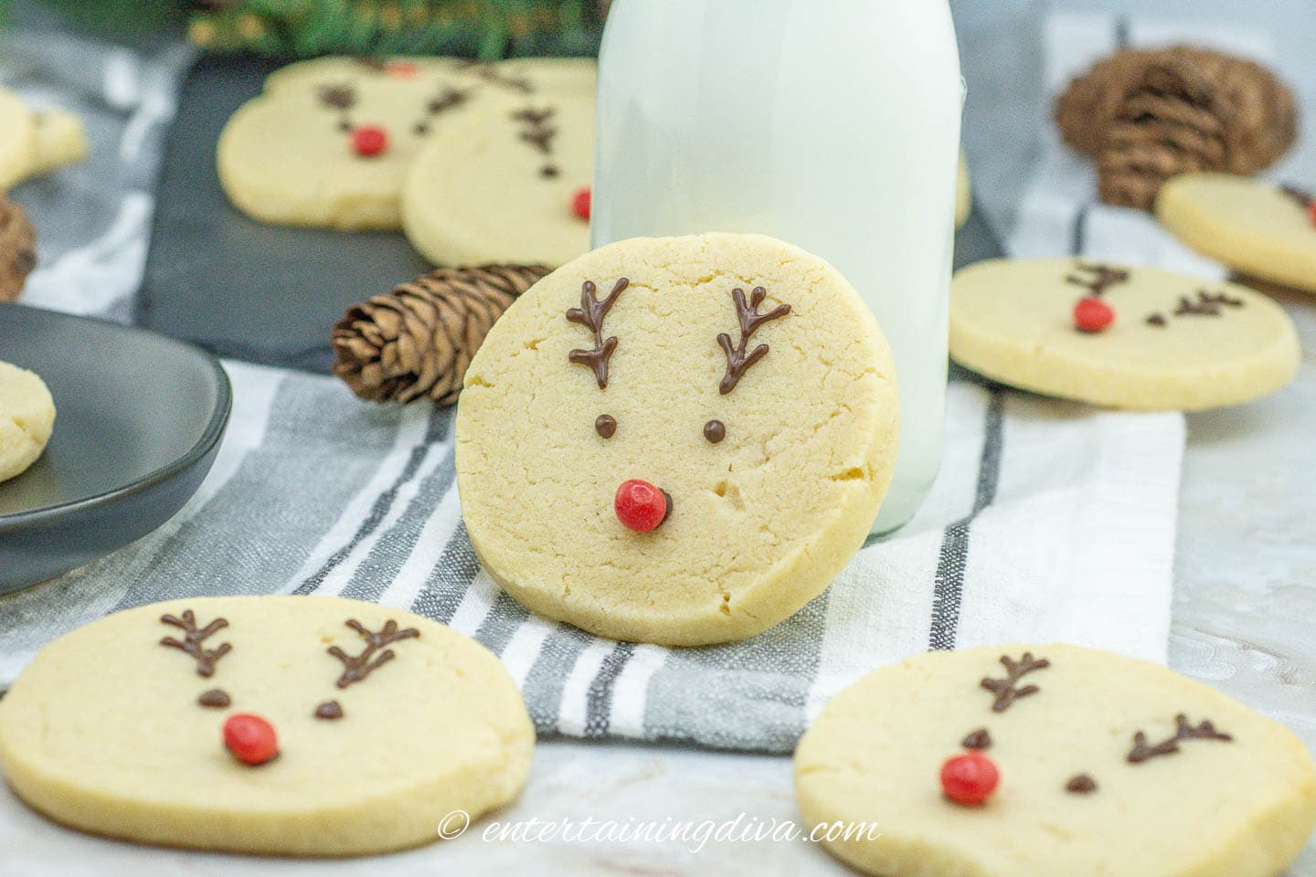 Reindeer sugar cookies on a table next to a bottle of milk.
