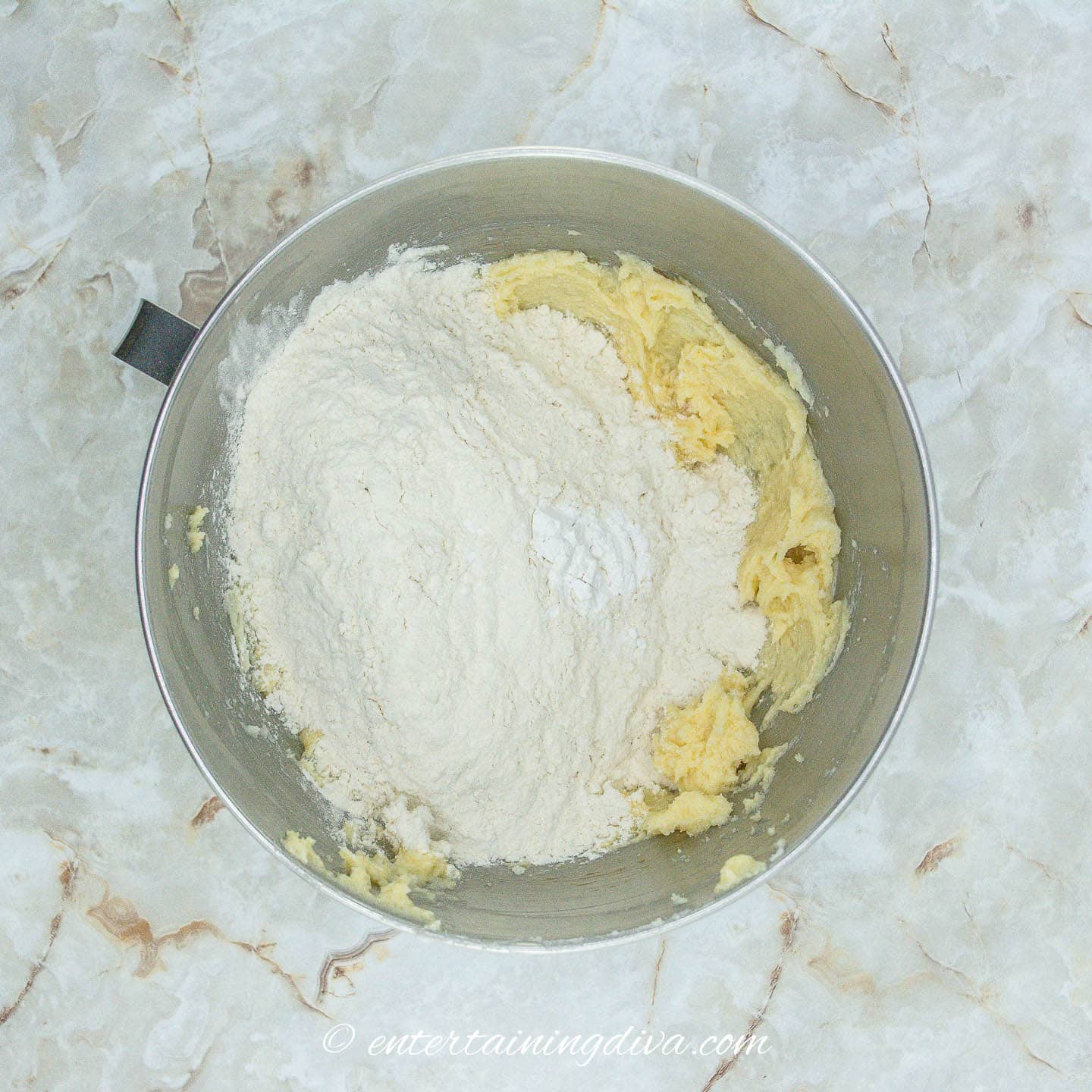 Flour on top of butter mixture in a bowl