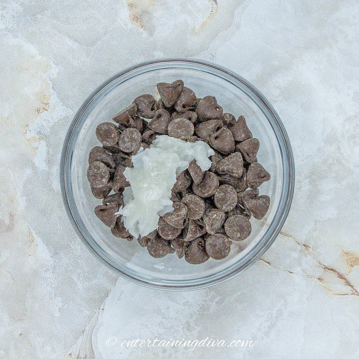 A glass bowl with chocolate chips and coconut oil.