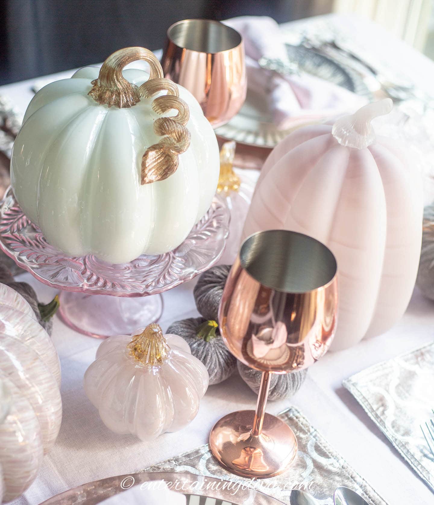 pink and white glass pumpkins on a fall tablescape with copper wine glasses
