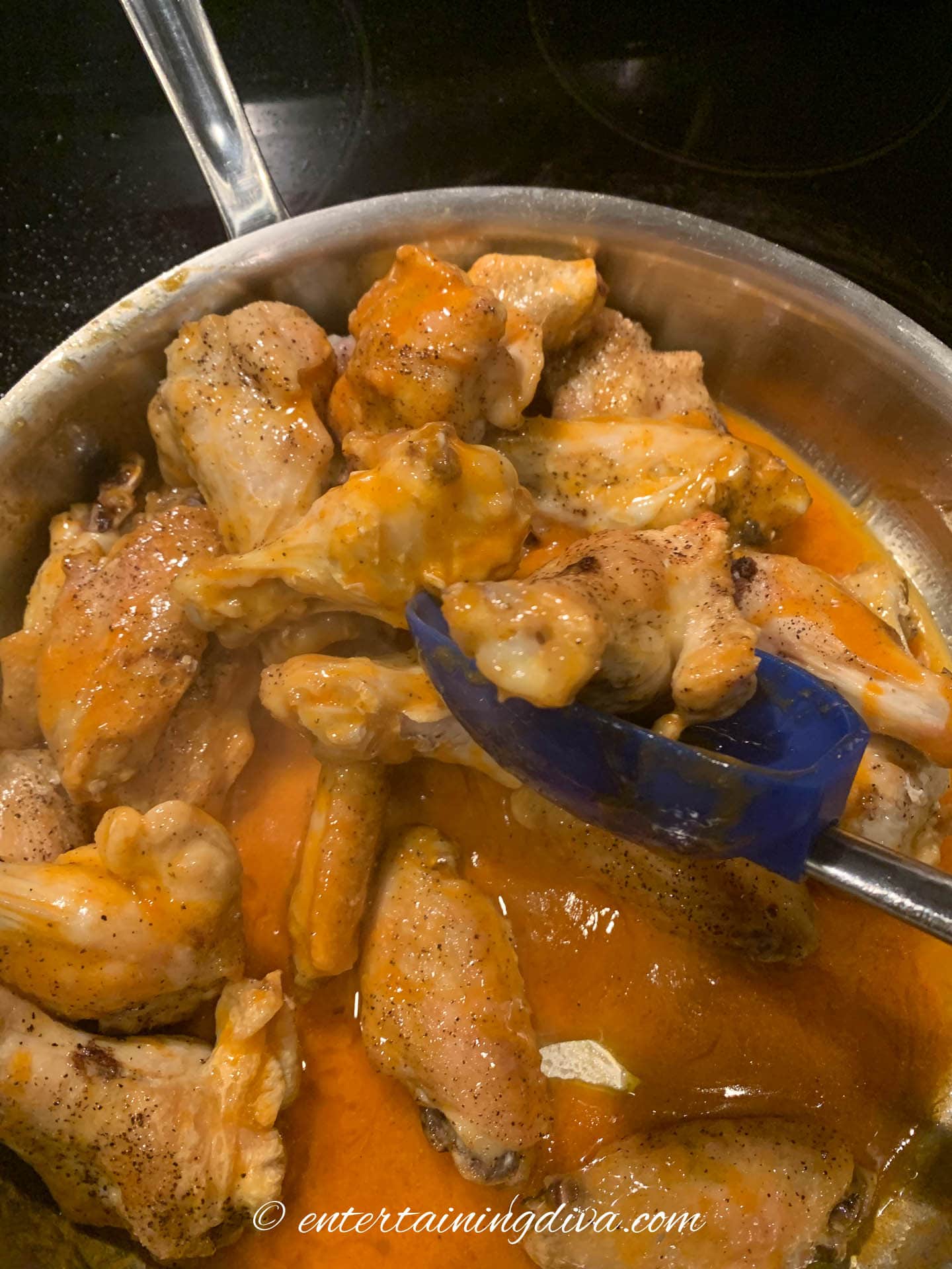 Baked wings being tossed in the buffalo sauce