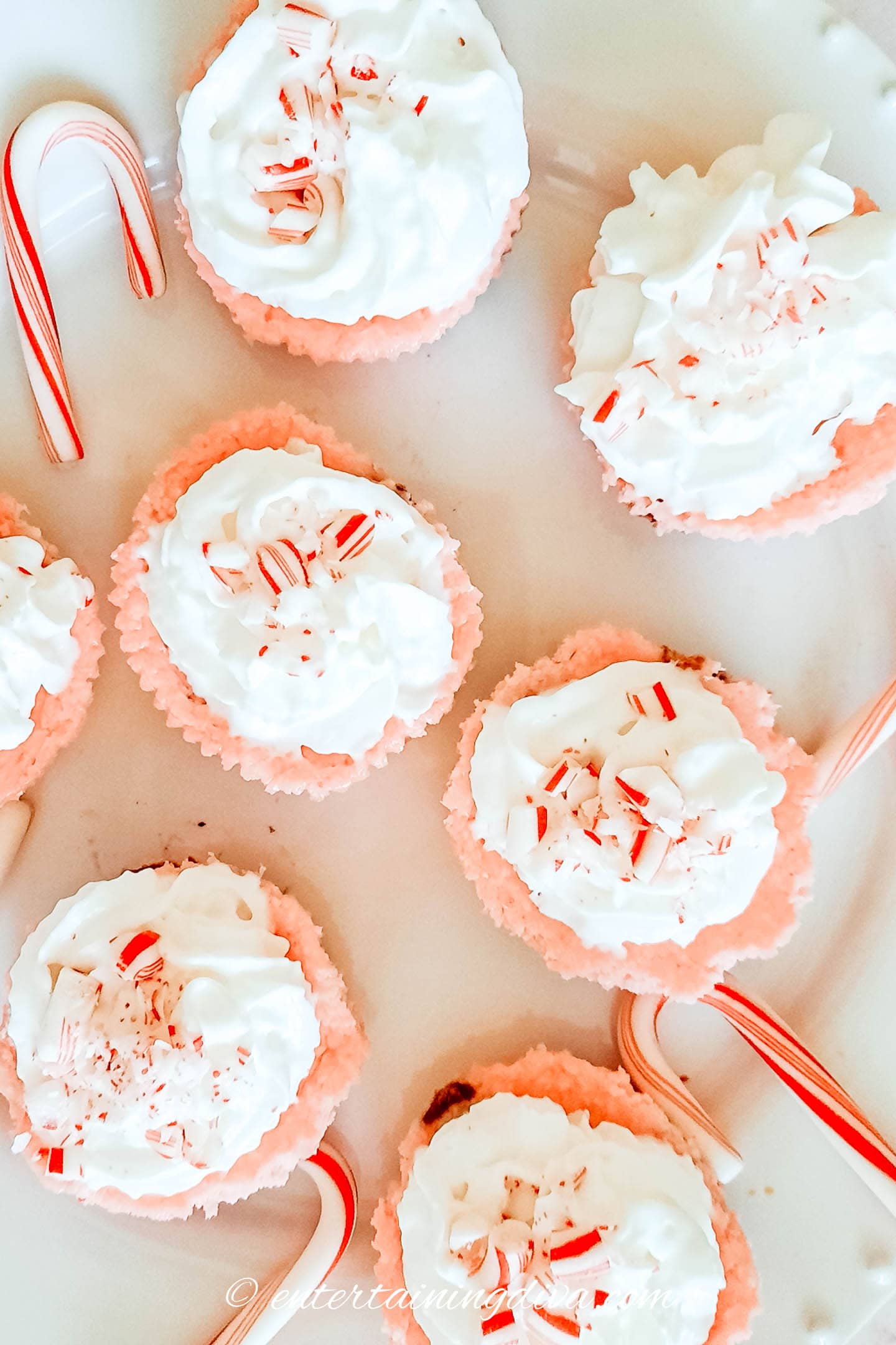 peppermint cheesecake cupcakes topped with whipping cream and crushed candy canes