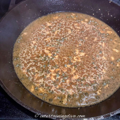 piccata sauce with capers simmering in a cast iron pan