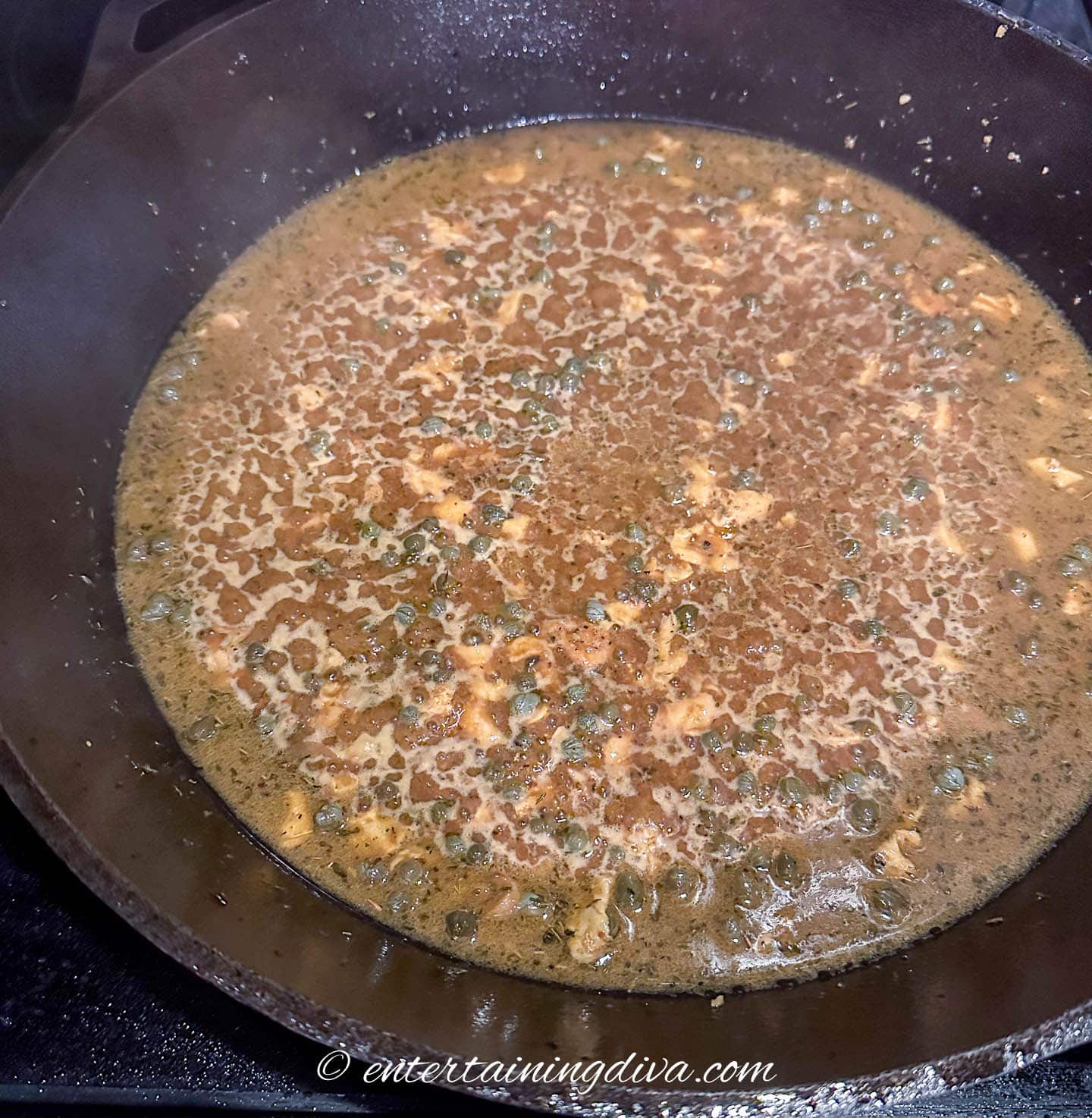 piccata sauce with capers simmering in a cast iron pan