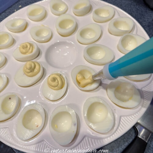 Deviled egg yolk mixture being piped into egg whites