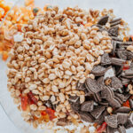 Popcorn, candy pumpkins, mini Reese's, gummy worms, salted peanuts and chopped Oreos in a bowl