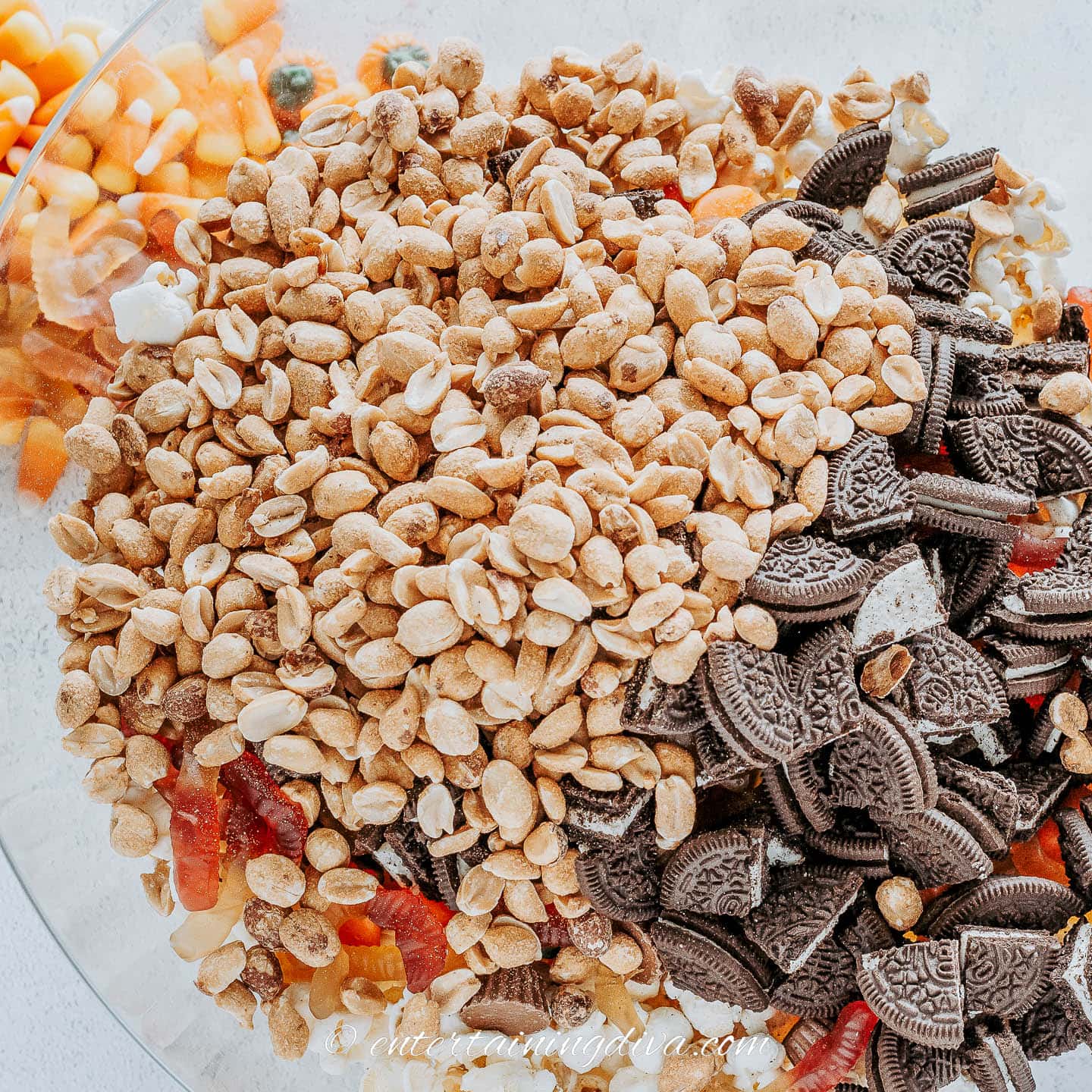 Popcorn, candy pumpkins, mini Reese's, gummy worms, salted peanuts and chopped Oreos in a bowl