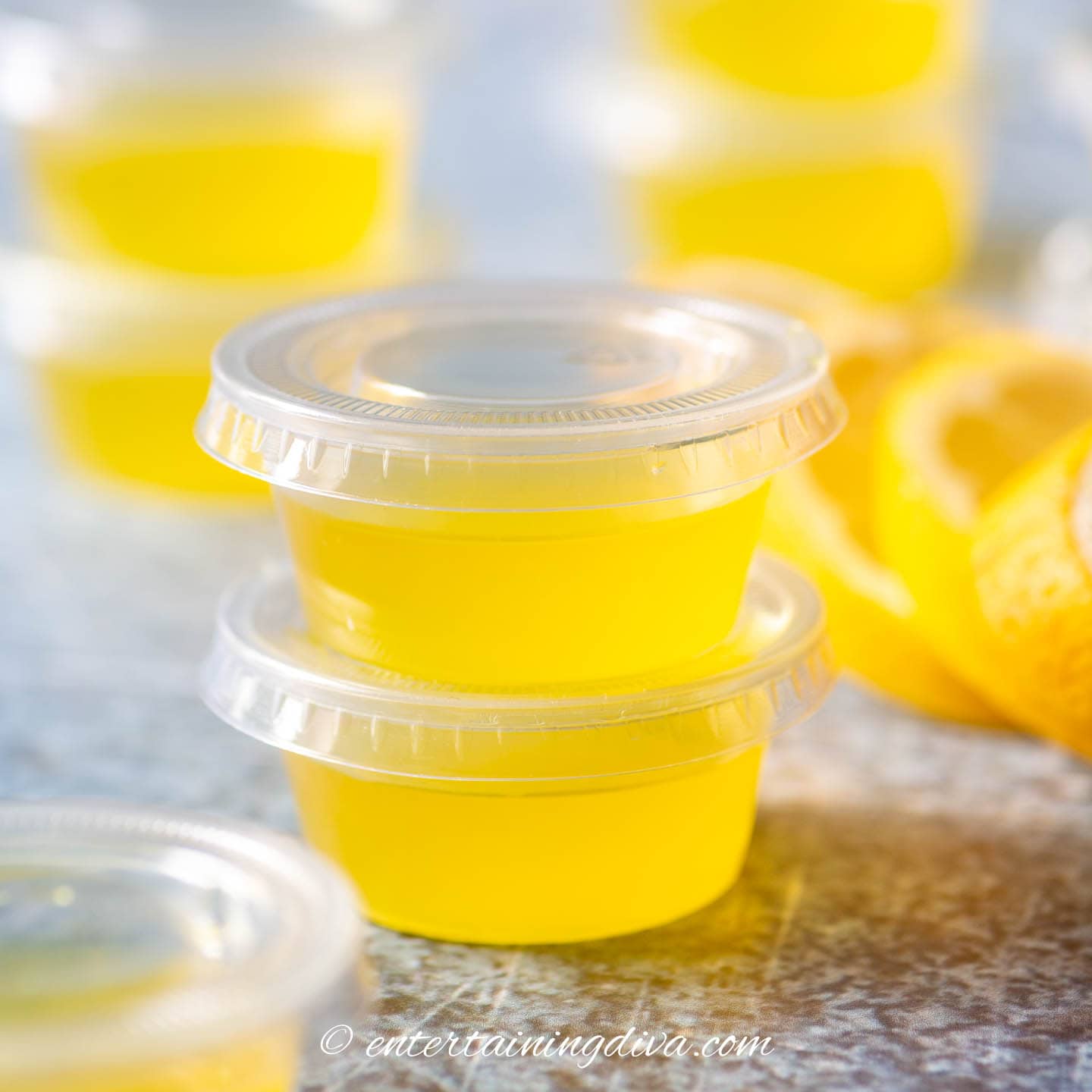 a stack of lemon drop jello shots in shot cups with lids