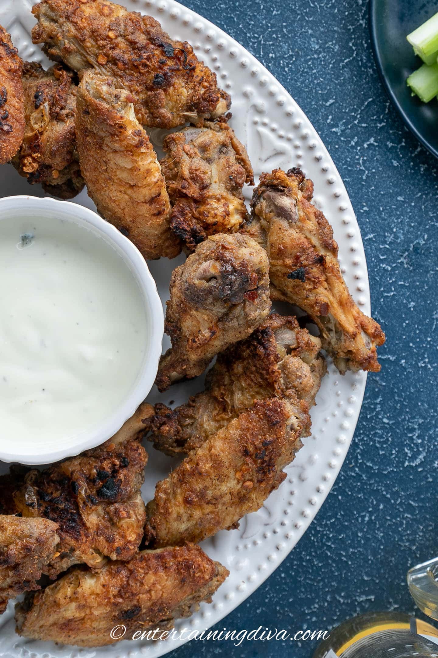 overhead view of marinated Asian spice wings on a plate with a bowl of blue cheese dressing