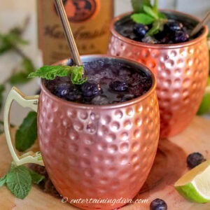 A close up of a blueberry moscow mule with mint in a copper mug